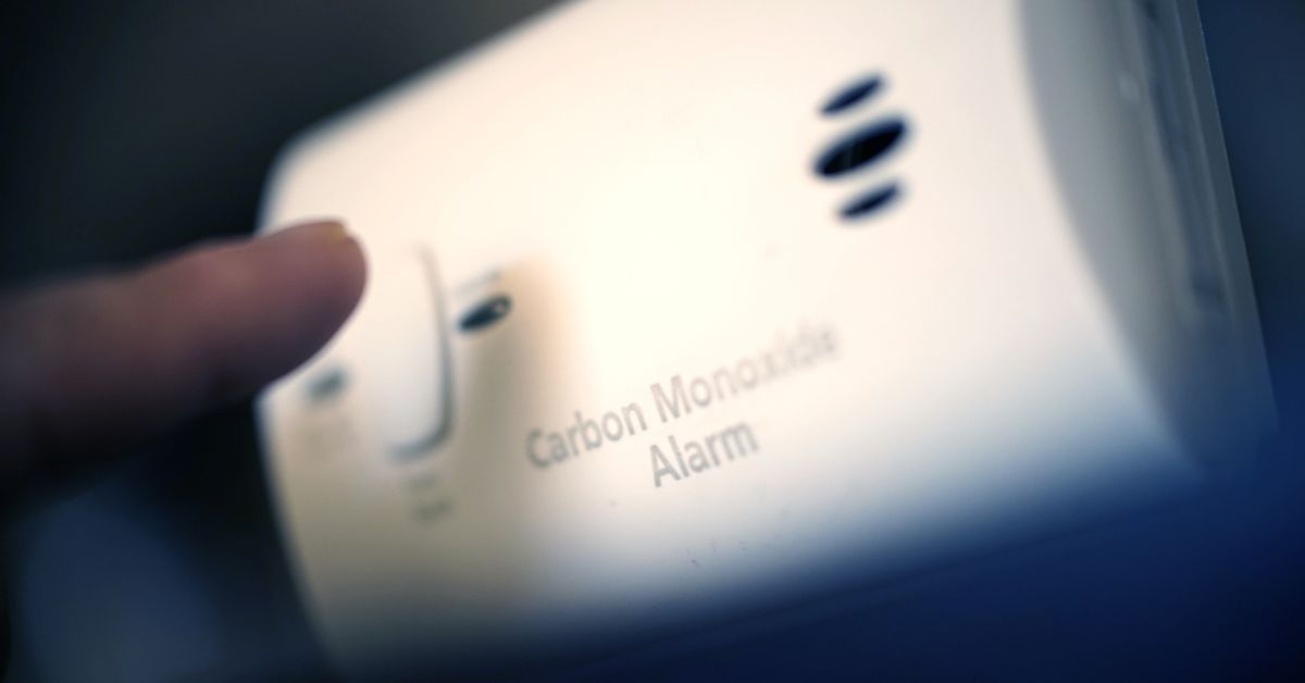 Selective focus photo of a person hitting a button on a carbon monoxide alarm.